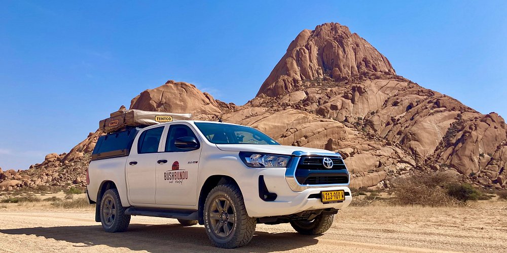 bushbundu-car-rental-windhoek-namibia-image-of-4x4-toyota-hilux-in-the-desert-branded-with-bushbundu-logo