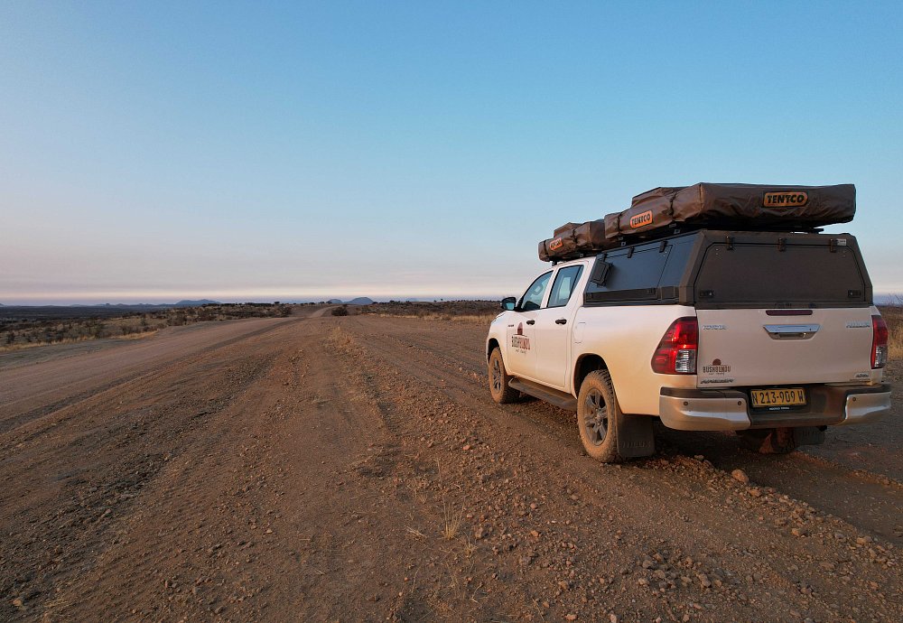 bushbundu-car-rental-windhoek-namibia-image-of-toyota-hilux-branded-with-bushbundu-logo-on-a-desert-road