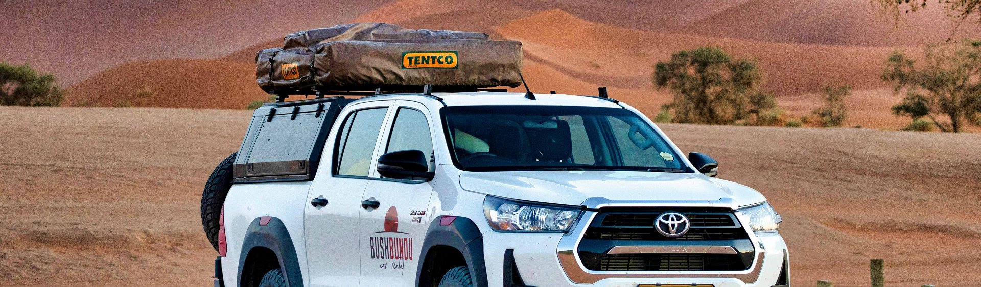 bushbundu-car-rental-windhoek-namibia-image-of-toyota-hilux-in-the-desert-with-bushbundu-logo-fleet-page-cover-image